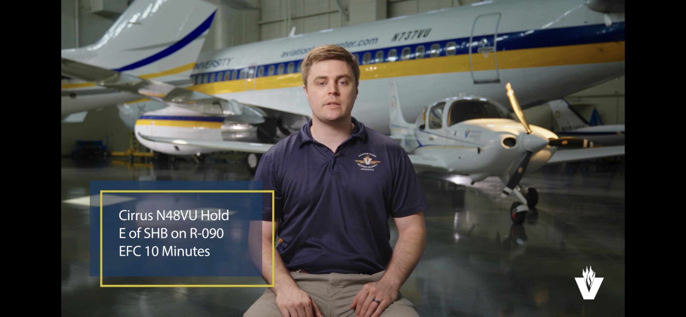 VU aviation instructor sitting while a VU aircraft emblazoned with the university's colors is behind him. 