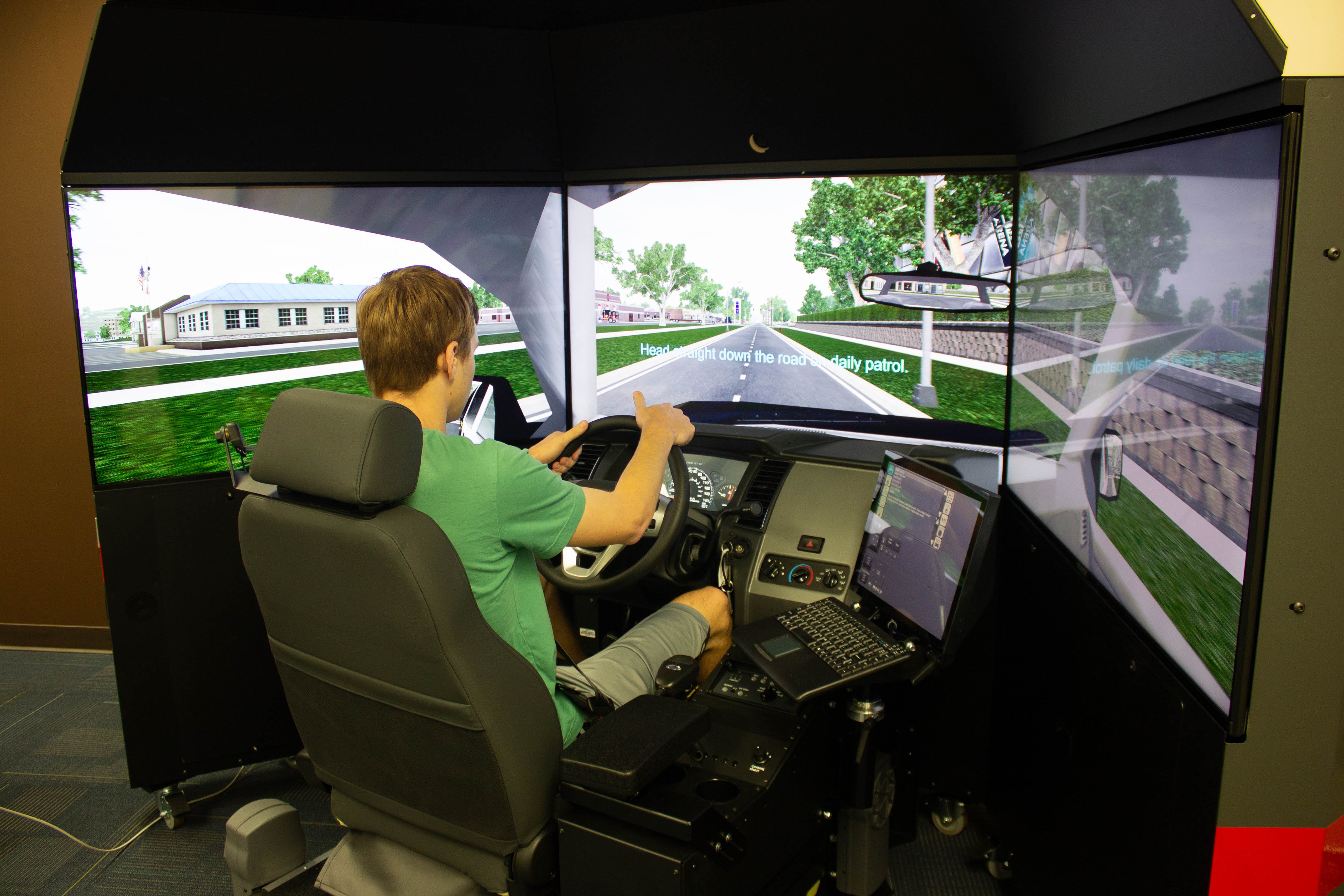 A male VU student holds the steering wheel of a law enforcement driving simulator